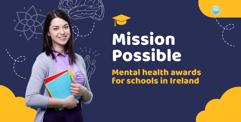 A young female teacher smiles to camera as she holds a pile of coloured notebooks.