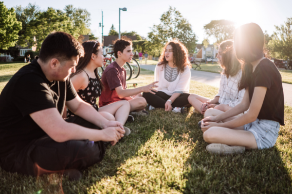 Group of teenagers sitting together in a park socialising