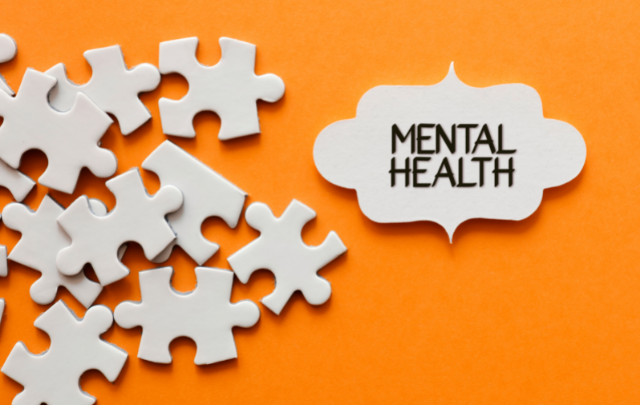 Jigsaw pieces are scattered around a single piece showing the words "mental health", all on an orange background