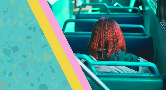 Image of the back of the head of a woman who is sitting on a bus seat in an empty bus