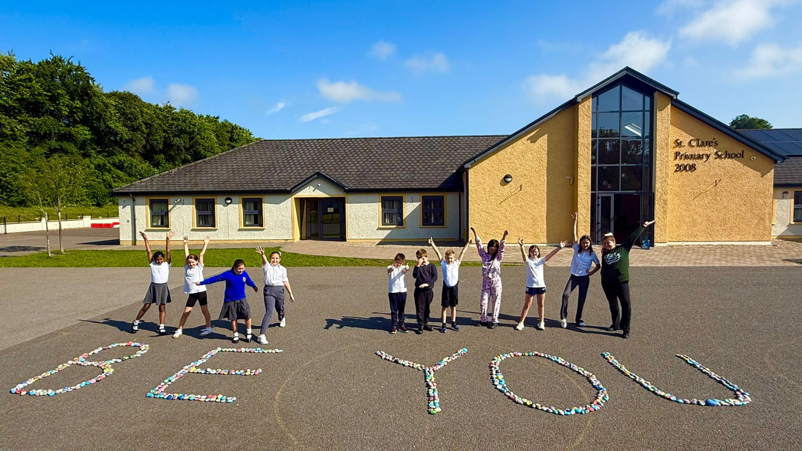 This is an image of a group of 11 primary school pupils outside their County Cavan school. The students are standing beside pebbles that are making up the words "Be You".