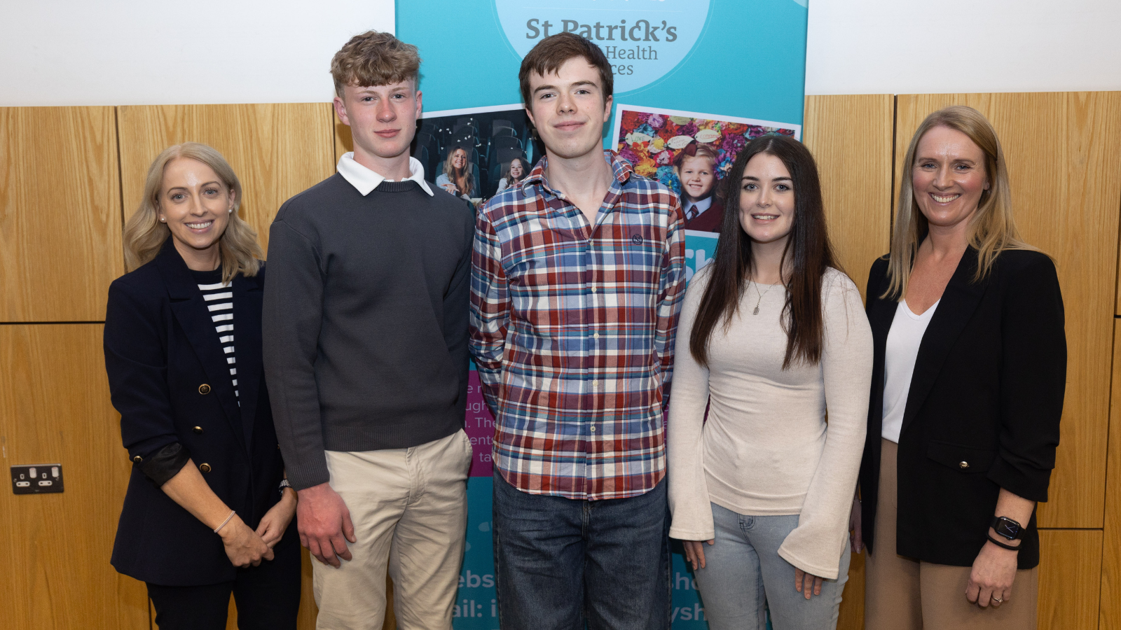 This is an image  of two staff from Walk in My Shoes with three students that completed the Transition Year Programme. They are standing in front of a Walk in My Shoes promotional banner.