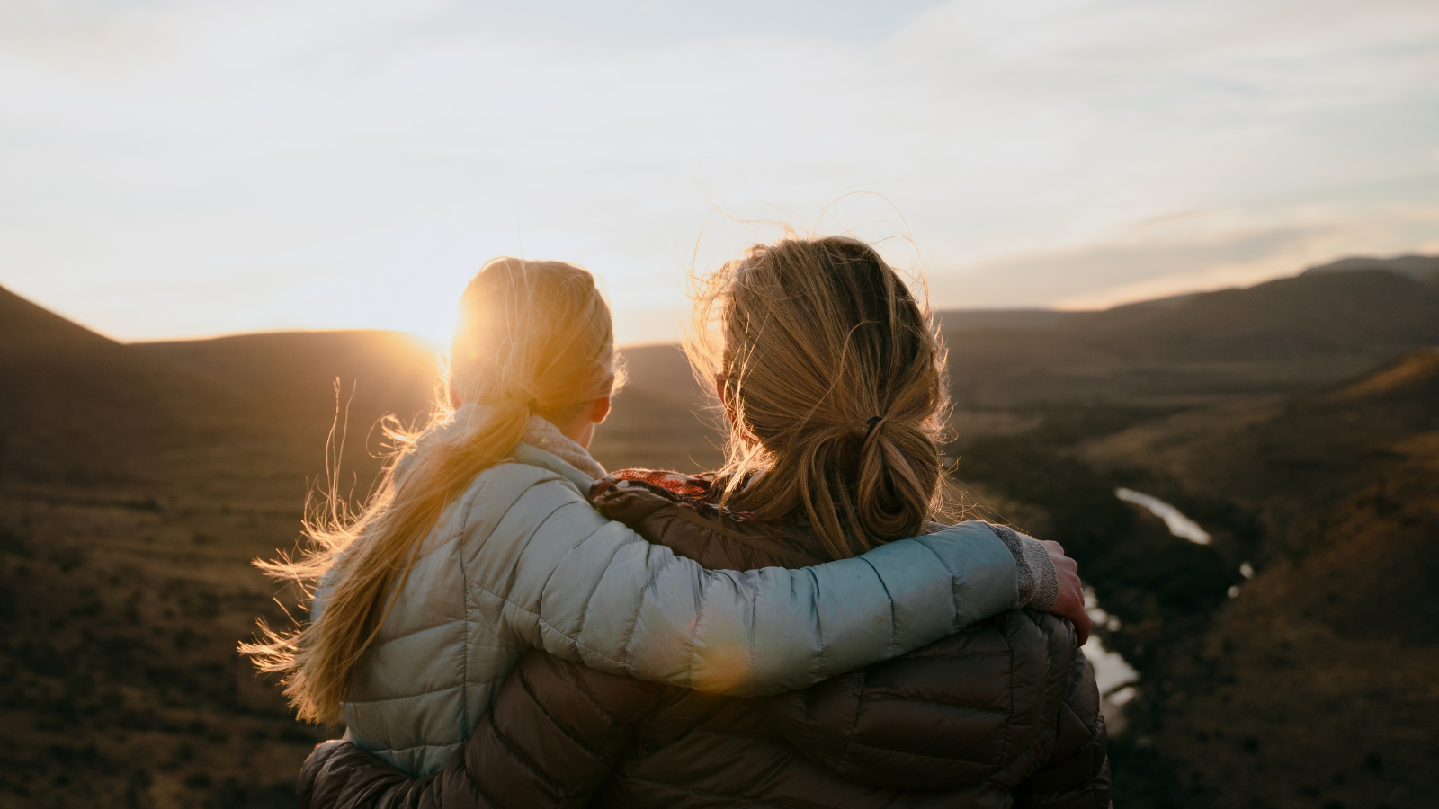 This is an image of a mother and daughter enjoying the view after a mountain hike during sunset.